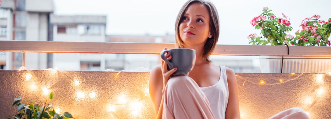 enjoying a cup of coffee on a lit balcony