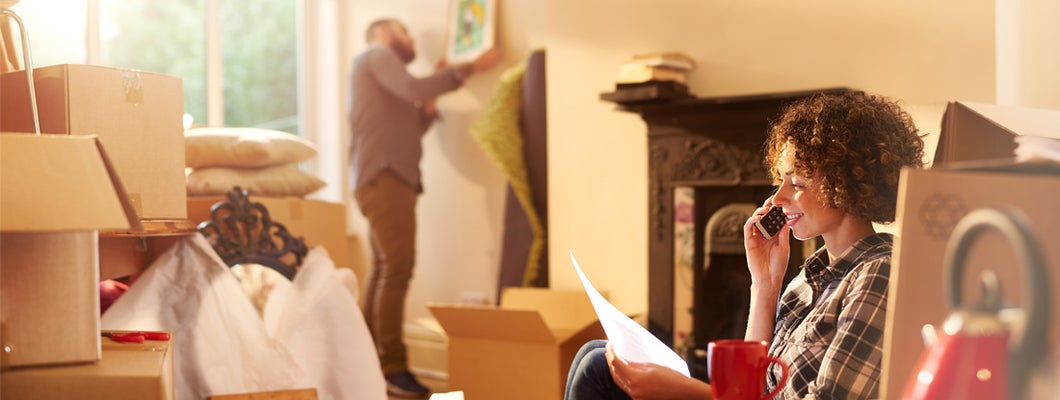 a couple move into their new home while woman talks on the phone whilst referring to a mortgage gift letter that she is holding