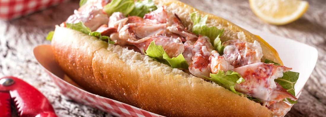 A delicious lobster roll on a rustic wood table top.