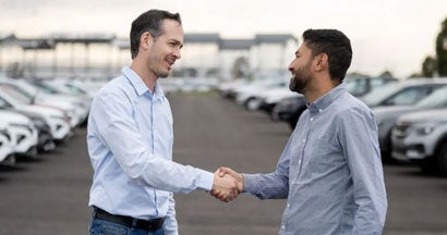 Salesman handshaking with a client after buying a car. How to Buy a Repo Car.
