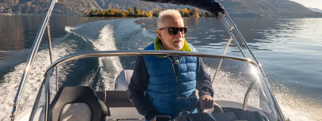 Man piloting boat on lake in Autumn. Find Colorado Boat Insurance.
