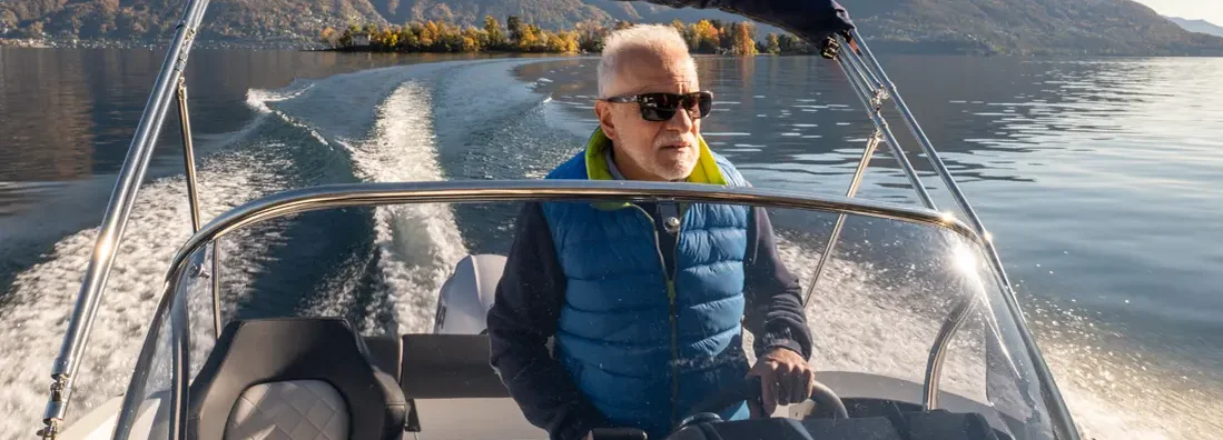 Man piloting boat on lake in Autumn. Find Colorado Boat Insurance.