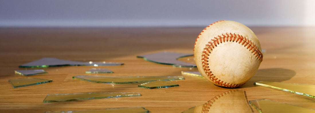 Baseball with Broken Window glass on wood floor. Homeowners Insurance for Non-Auto Accidents Away from Home.