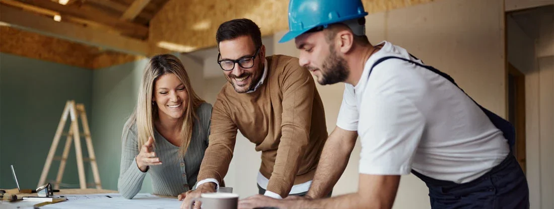 Couple analyzing blueprints with their construction worker. Find Home Renovation Insurance.