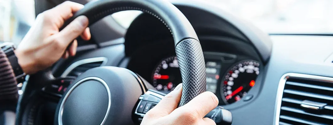 Man driving modern car, holding steering wheel in city traffic. Top 20 Defensive Driving Tips to Keep You Safe. 