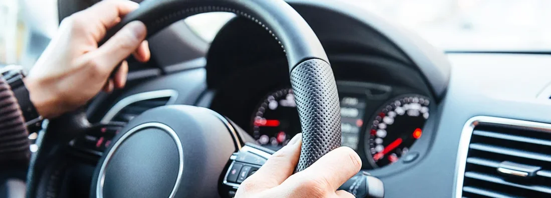 Man driving modern car, holding steering wheel in city traffic. Top 20 Defensive Driving Tips to Keep You Safe. 