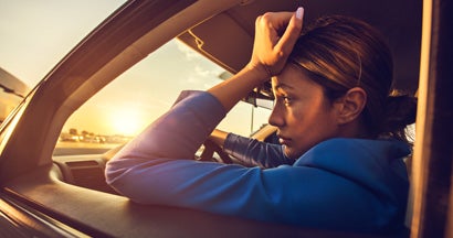 Sad woman having problems while driving a car at sunset. This is why your car insurance is making you broke.