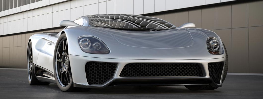 A silver sports car next to a building. Find exotic car insurance.