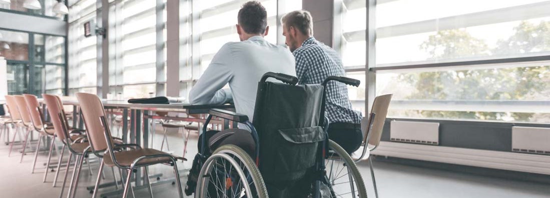 Disabled businessman working with his colleague in an office. What Is a Return to Work Program?