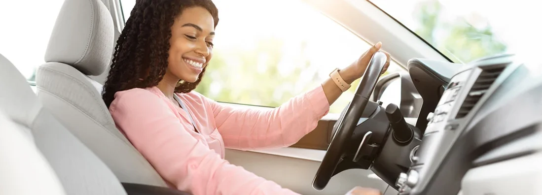 Smiling woman driving her new car in city. Find College Grove, Tennessee car insurance.
