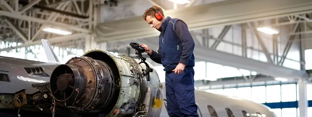 Aircraft engineer in the hangar repairing and maintaining airplane jet engine. Find Industrial Insurance.