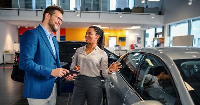 Salesman helping the male customer to choose a new car. 7 Tips To Get the Best Deal On a New Car.