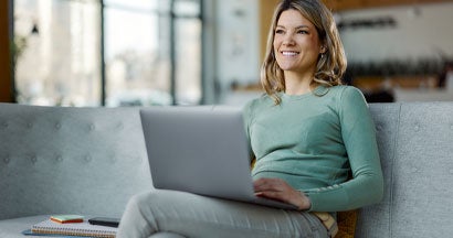 Woman using laptop on sofa in a hallway. 5 Pros and Cons of Buying a Car Online. 