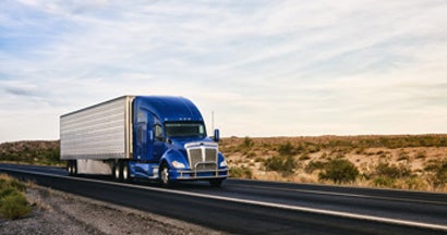 Semi truck on highway through desert in New Mexico. Find Commercial Truck Insurance.