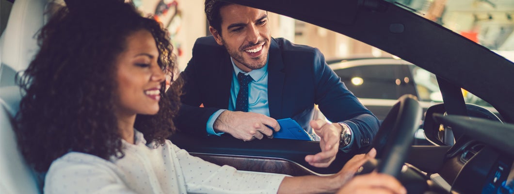 Smiling woman in the showroom enjoying luxury car