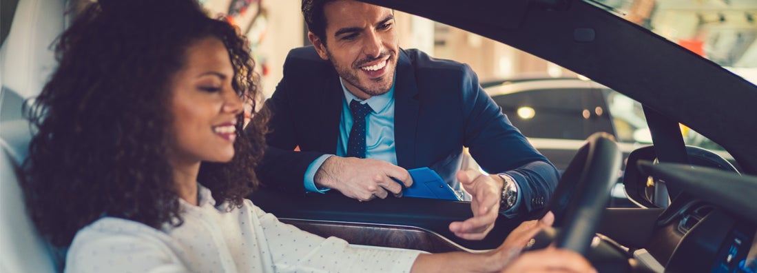 Smiling woman in the showroom enjoying luxury car