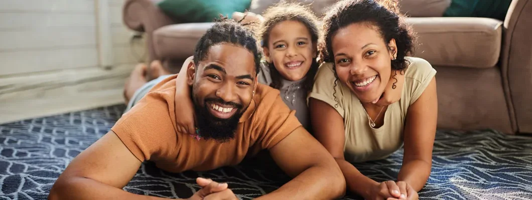 Happy black family relaxing on carpet at home. Find Alabama Life Insurance.