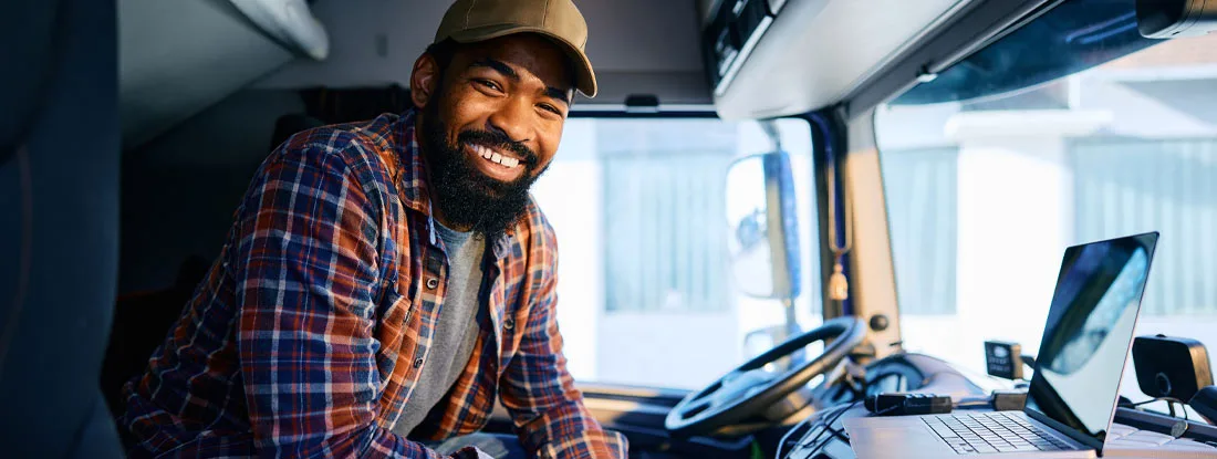 Truck driver using laptop. Workers' Comp for Truck Drivers and Trucking Companies.