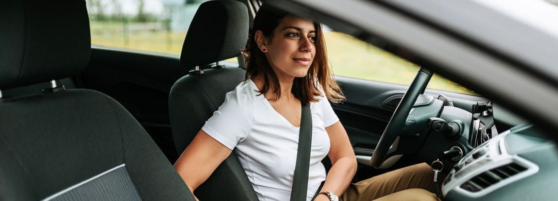 Woman sitting in a car putting on her seat belt. Find Columbia Missouri car insurance.