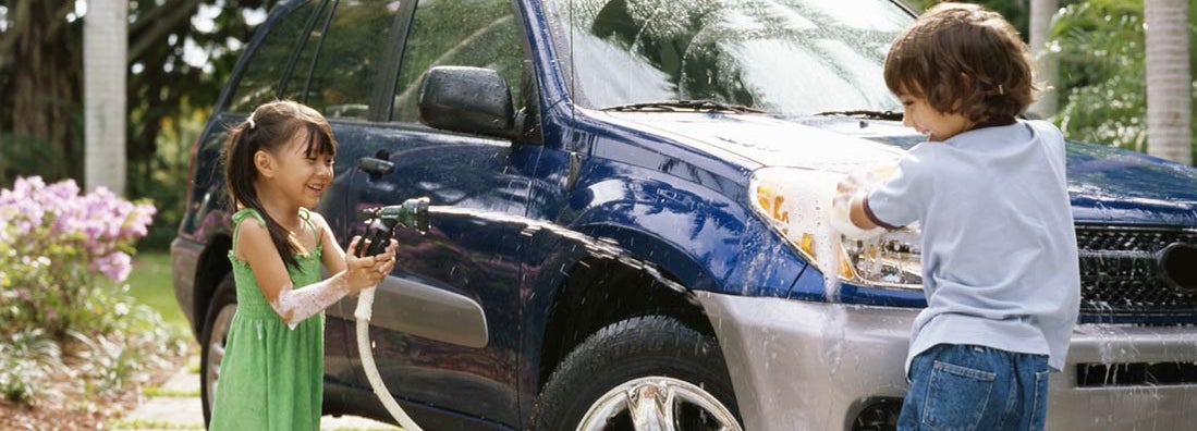 Children washing car on driveway. Find Fresno California car insurance.