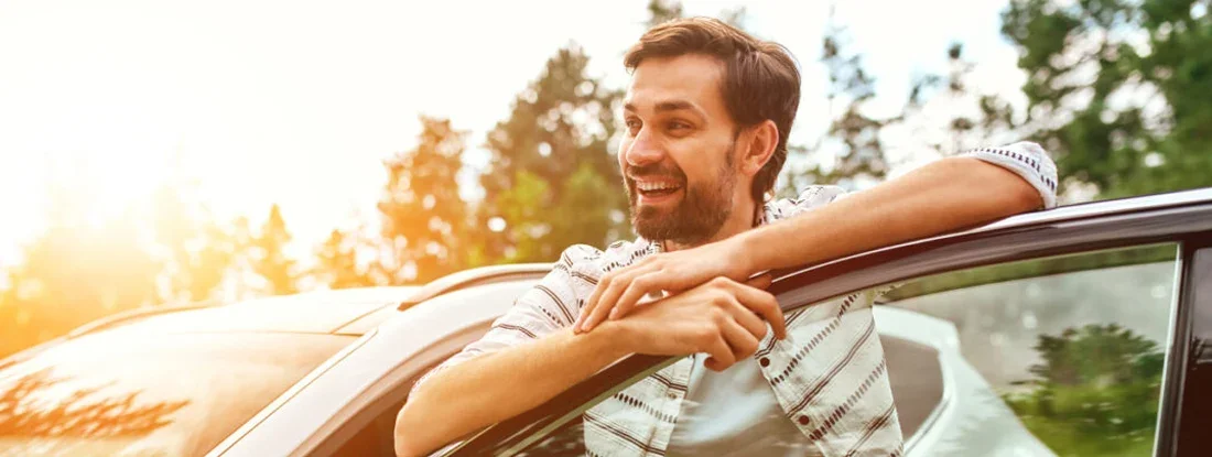Man stands near the car on the background of the forest. 8 of the Best Used Cars Under $15,000.