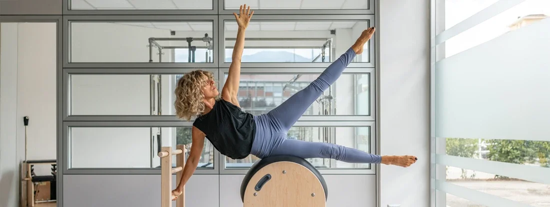 Pilates studio gym: Instructor on ladder barrel. Find Pilates Instructor Insurance.