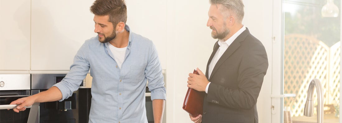 Man looking for new home, checking kitchen equipment during meeting with real estate agent