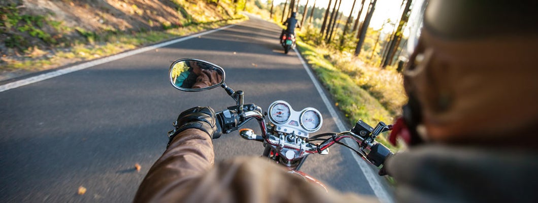 Man driving motorcycle on forest road. Find Virginia Motorcycle Insurance.