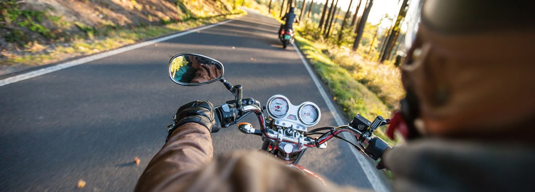 Man driving motorcycle on forest road. Find Virginia Motorcycle Insurance.