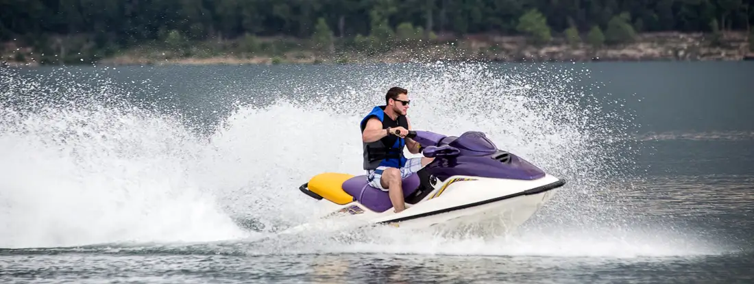 Young man riding jet boat on a summer day at the lake. Find Sea-Doo Insurance.