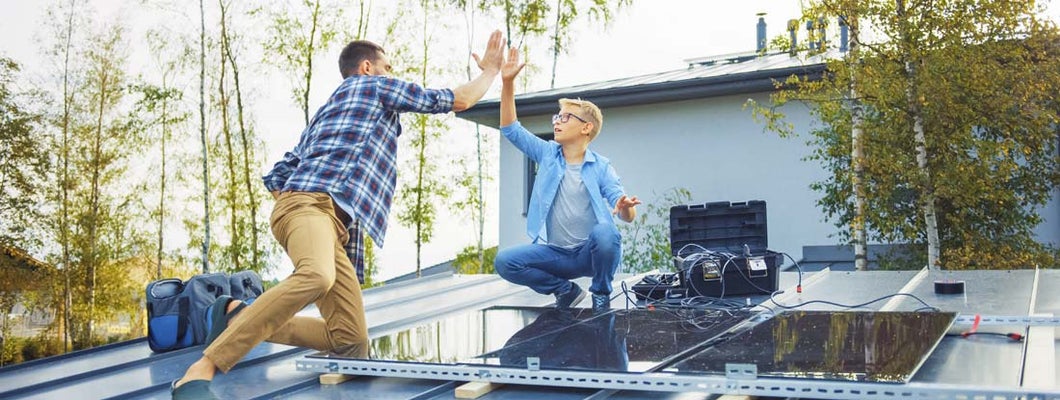 Father and Son Installing Solar Panels to a Metal Basis with a Drill. Eco friendly things you can do for your home.