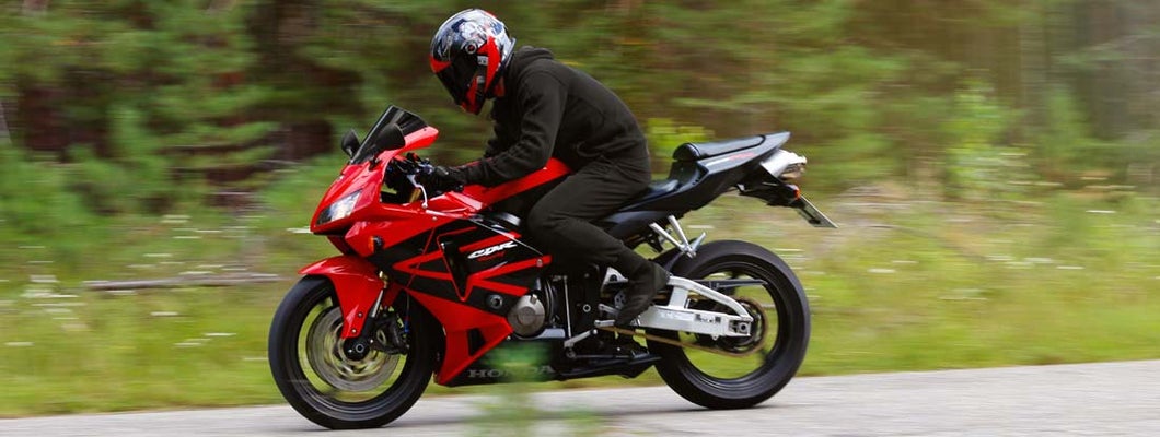 Motorcyclist wearing a helmet with a black visor and red sport bike. Find Streetbike and Sportbike Insurance.