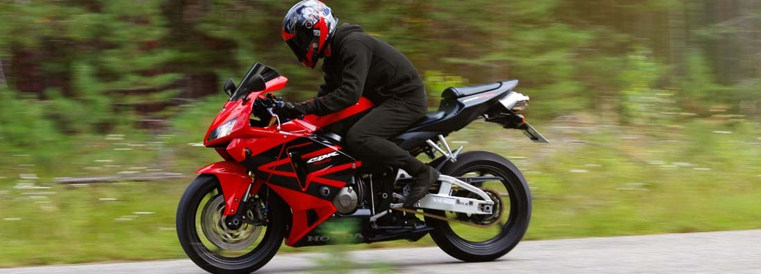 Motorcyclist wearing a helmet with a black visor and red sport bike. Find Streetbike and Sportbike Insurance.