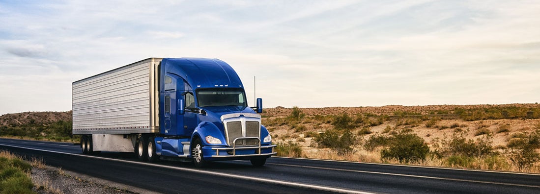 Semi truck on highway through desert in New Mexico. Find Commercial Truck Insurance.