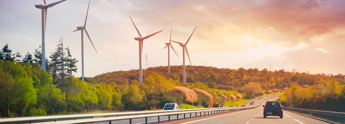 Cars going on highway in the landscape with wind propellers
