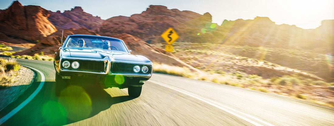 classic car going down a winding road through the mountains