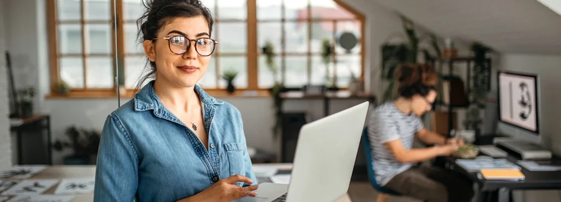 Office worker woman with laptop looking at camera. Business Insurance in Biddeford, Maine.