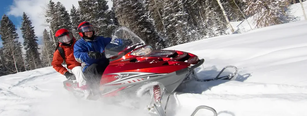 Couple Sitting on Snowmobile. Snowmobile Insurance 101.