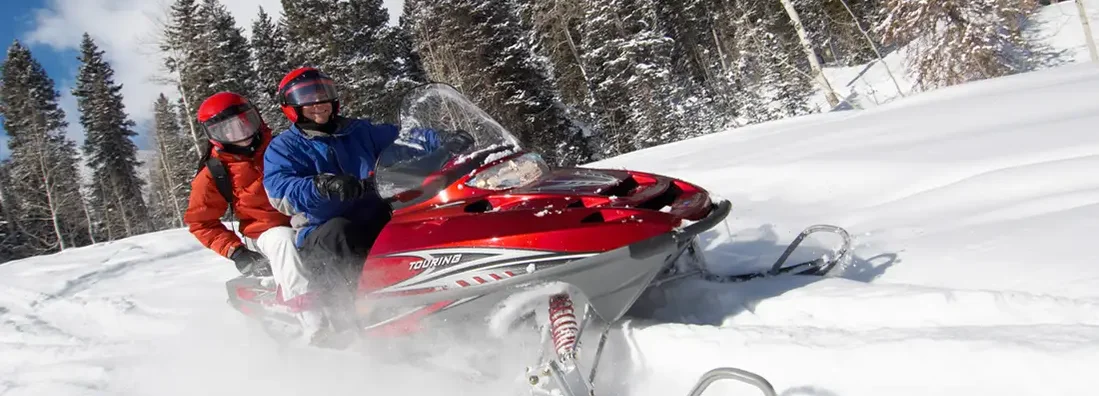 Couple Sitting on Snowmobile. Snowmobile Insurance 101.