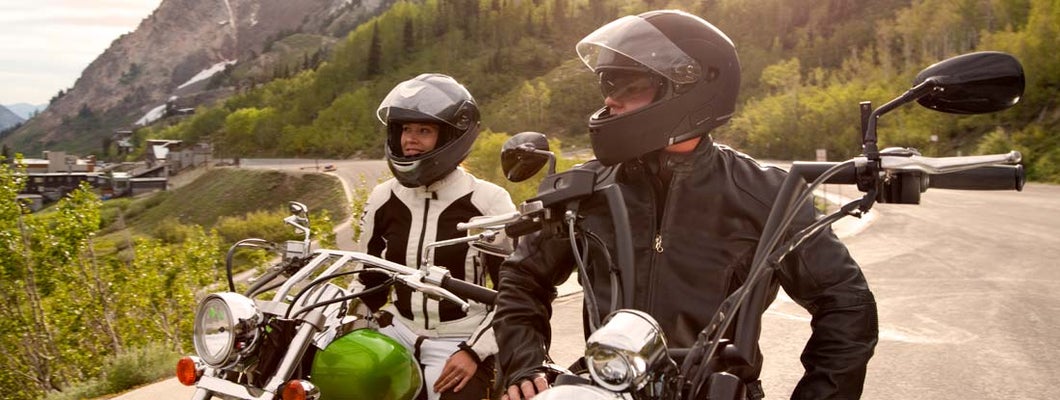 Motorcycle couple parked and enjoying view of snow capped mountains. Find Colorado Motorcycle Insurance.