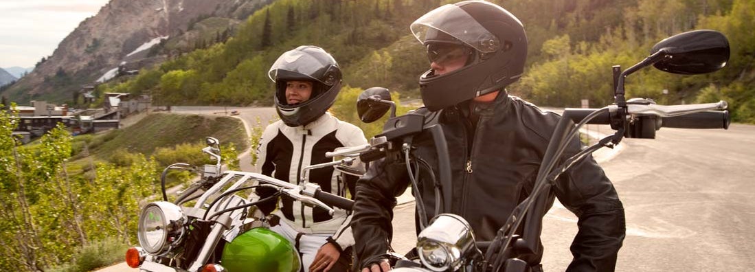 Motorcycle couple parked and enjoying view of snow capped mountains. Find Colorado Motorcycle Insurance.