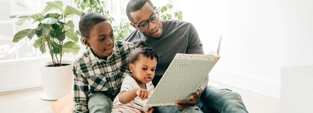 Dad reading a book for his kids at home. Compare Life Insurance Companies from 2022. 