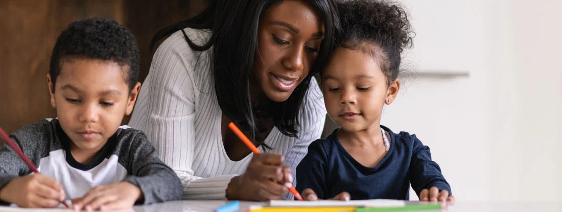 Mother helping her two children with their lessons. Will my homeowners insurance cover a home-schooling pod?