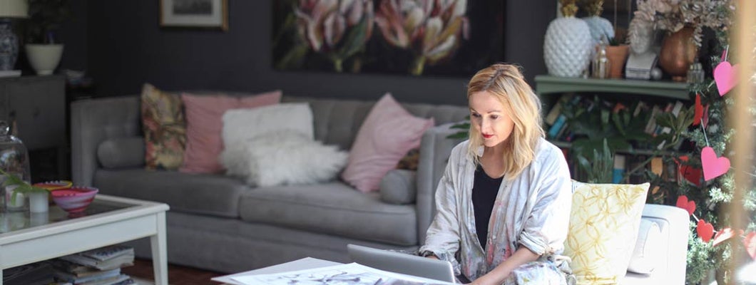 Woman checking her emails on the sofa at home. Find Fine Art Insurance.