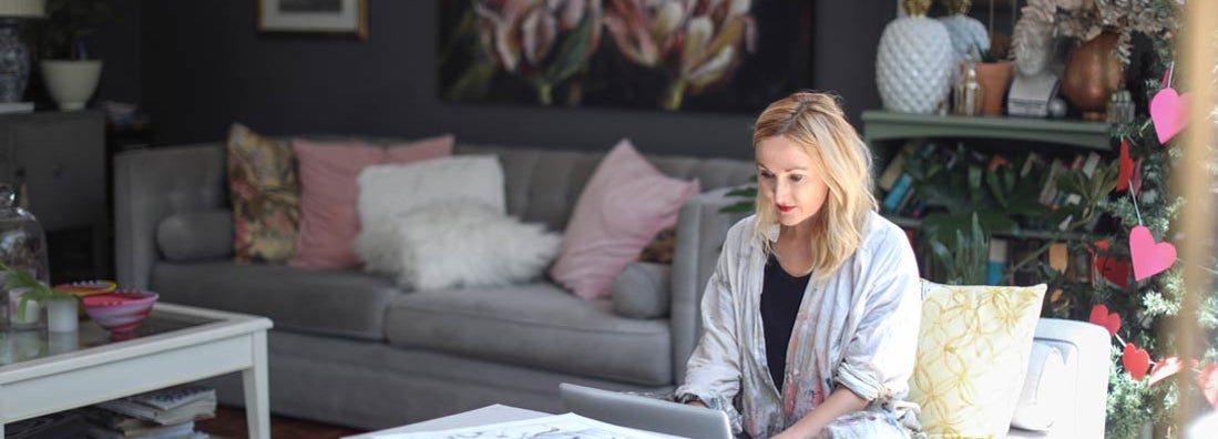 Woman checking her emails on the sofa at home. Find Fine Art Insurance.