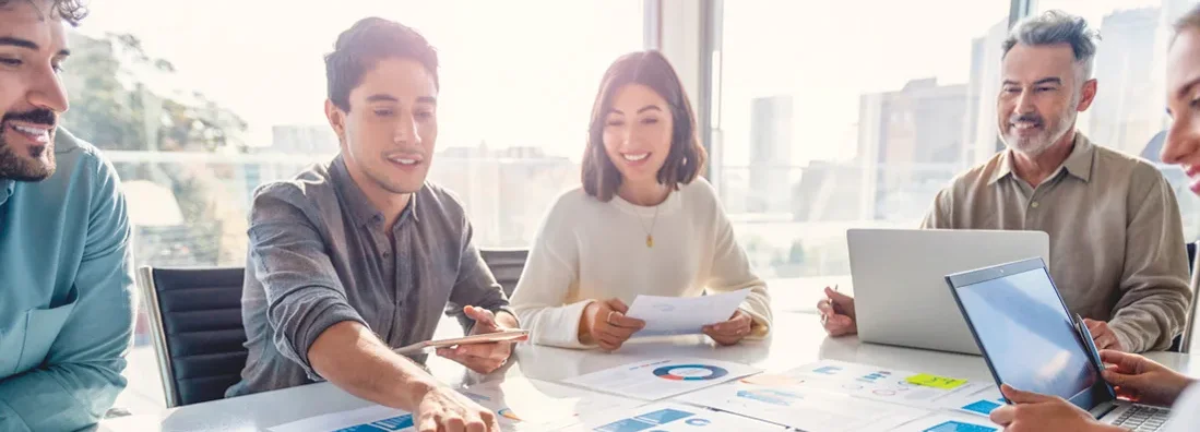 Group of co-workers working on a board room table at a business presentation. Find Palo Alto business insurance.