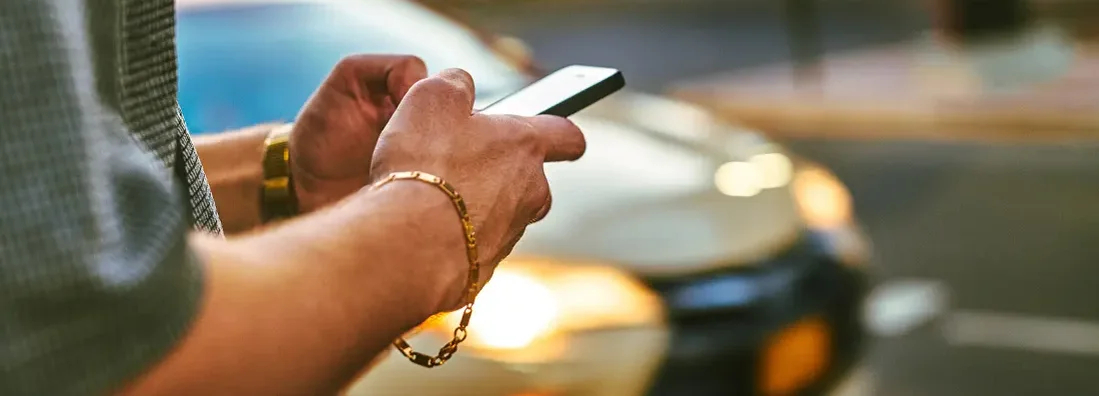 Man using phone standing near car. How to Find the Best Car Insurance Coverage in Great Neck, New York.