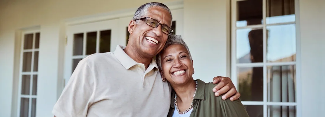 Senior couple smile outside of their home. The difference between landlord and homeowners insurance.