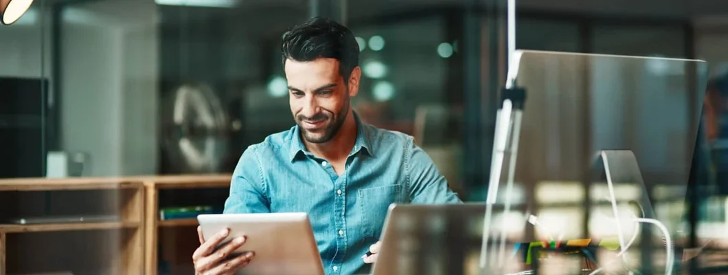 Businessman using a digital tablet at his desk in a modern office. Find Technology Business & IT Insurance.