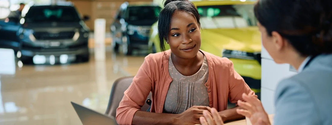 Woman having a meeting with car salesperson in showroom. Are Zero Down Payment Car Loans a Good Idea?